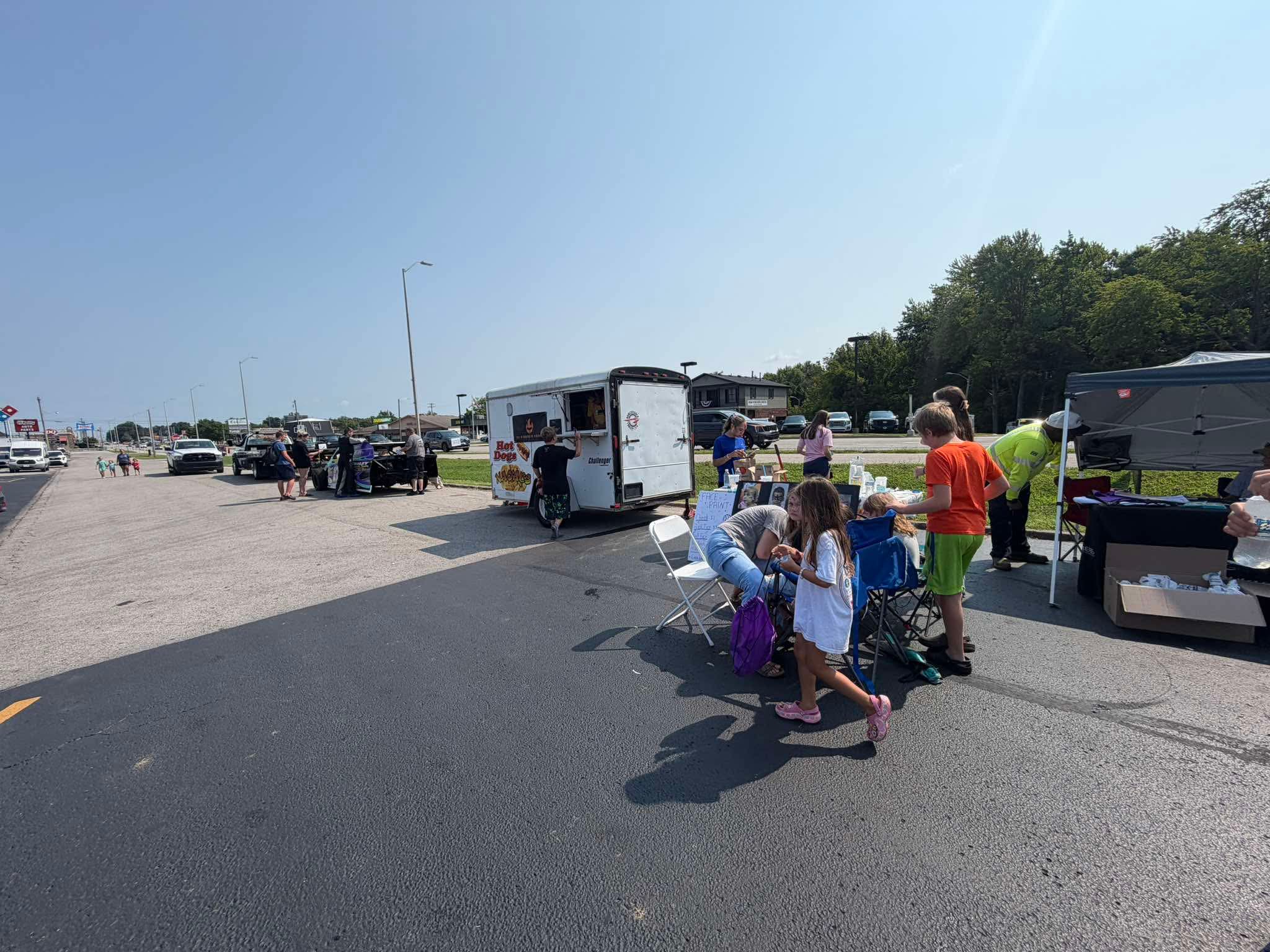 Families visiting food vendors and community booths outside The Twisted Willow Barbershop